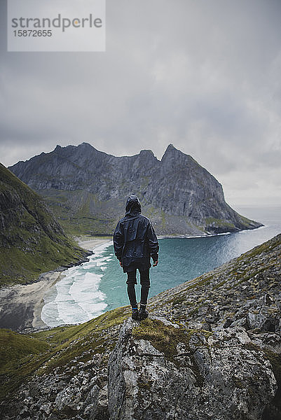 Mann steht auf einem Felsen am Strand von Kvalvika auf den Lofoten  Norwegen