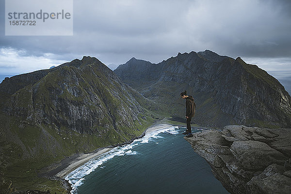 Mann steht auf einer Klippe am Berg Ryten auf den Lofoten  Norwegen