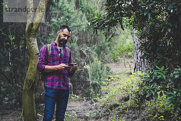 Mann benutzt Smartphone im Wald