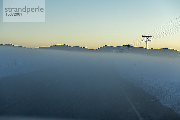 Straße im Nebel bei Sonnenaufgang