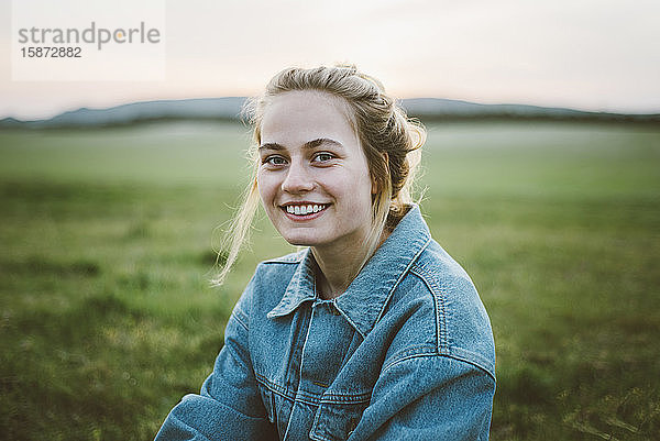 Lächelnde Frau in Jeansjacke auf einem Feld