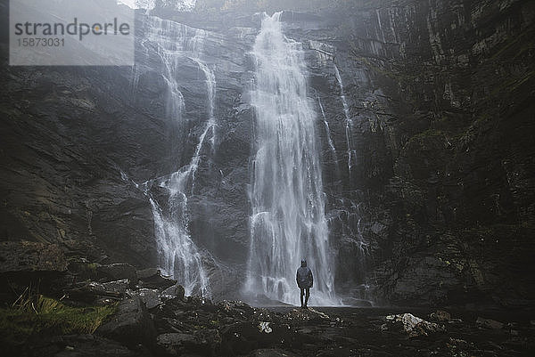 Mann vor dem Wasserfall Skjervefossen in Norwegen