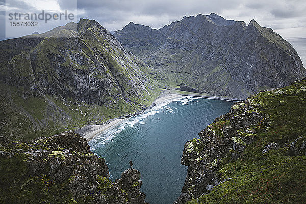 Mann steht auf einer Klippe am Berg Ryten auf den Lofoten  Norwegen