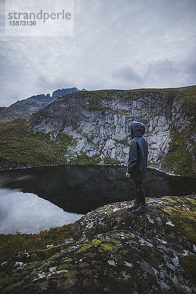 Mann steht auf einem Felsen am See auf den Lofoten  Norwegen