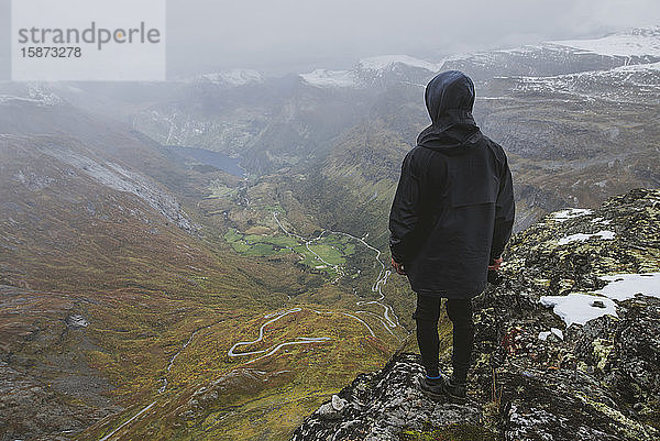 Mann mit Kamera auf dem Berg Dalsnibba mit Blick über das Tal in Geiranger  Norwegen