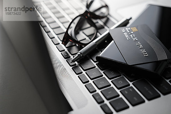 Kreditkarte  Smartphone  Stift und Brille auf der Laptop-Tastatur