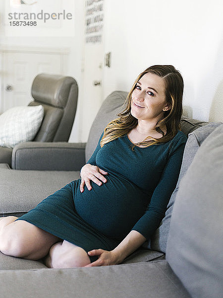 Porträt einer schwangeren Frau auf dem Sofa sitzend