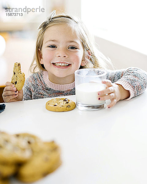 Mädchen isst Milch und Kekse