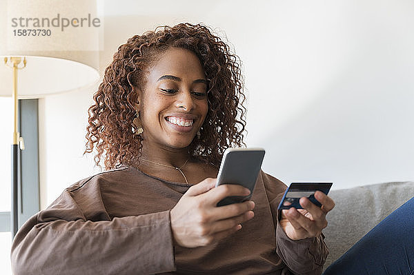 Lächelnde Frau mit Kreditkarte und Smartphone