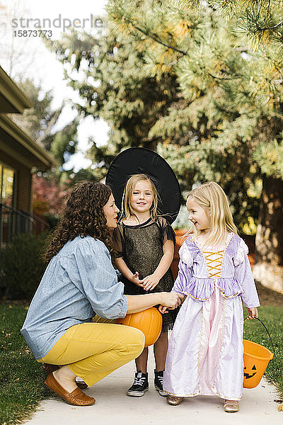 Mädchen in Halloween-Kostümen mit ihrer Mutter