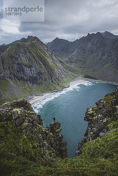 Mann steht auf einer Klippe am Berg Ryten auf den Lofoten  Norwegen