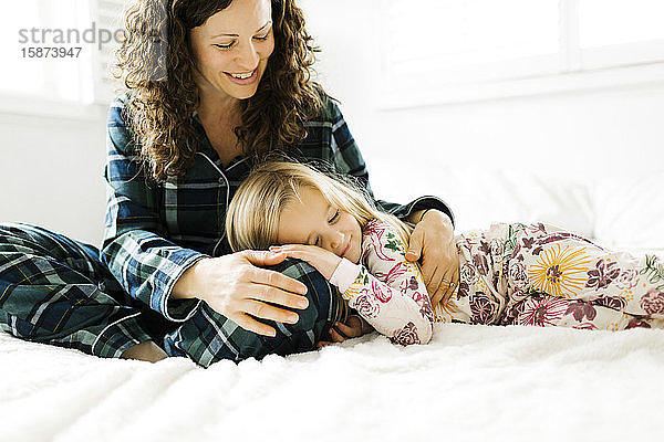 Mutter und Tochter umarmen sich auf dem Bett