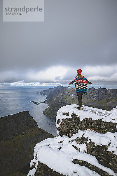 Junge Frau in roter Mütze und Pullover auf verschneitem Berg