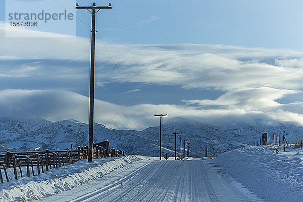 Verschneite Straße mit Bergen in der Ferne