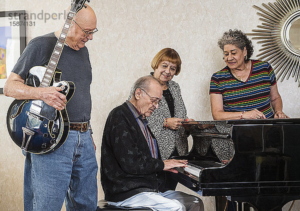 Ältere Menschen beobachten älteren Mann beim Klavierspielen