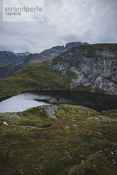 Mann steht auf einem Felsen am See auf den Lofoten  Norwegen