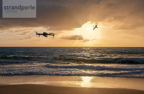 Drohne fliegt bei Sonnenuntergang über den Strand