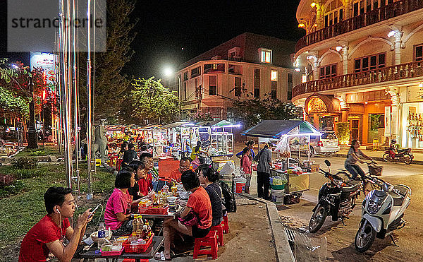 Käufer betrachten einen Marktstand mit farbenfroher Kleidung in der Pub Street in der Innenstadt von Siem Reap  Kambodscha  Asien. Siem Reap ist die Hauptstadt der Provinz Siem Reap. Die Pub Street ist ein bekanntes Ziel für ein lebhaftes Nachtleben für Touristen und Reisende  da die Restaurants und Bars bis spät in die Nacht geöffnet sind.