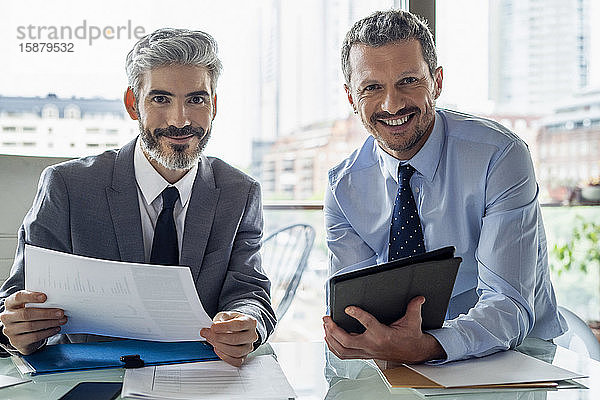 Lächelnde Geschäftsleute mit Dokument und digitalem Tablet