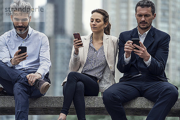 Geschäftsleute benutzen Smartphones in einem öffentlichen Park