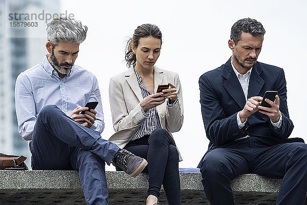 Geschäftsleute benutzen Smartphones in einem öffentlichen Park
