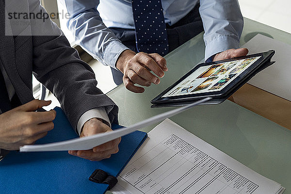Geschäftsleute halten ein Dokument und ein digitales Tablet
