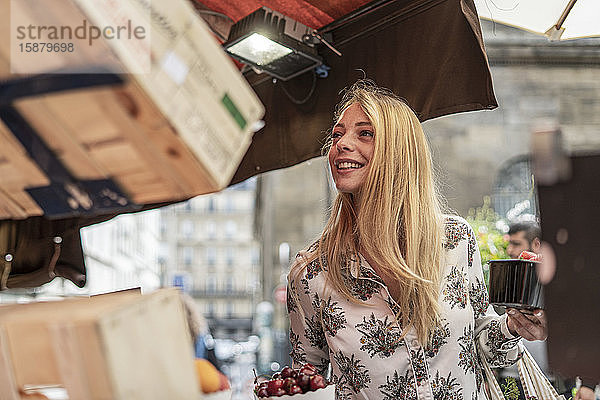 Junge Frau kauft Früchte an einem Marktstand