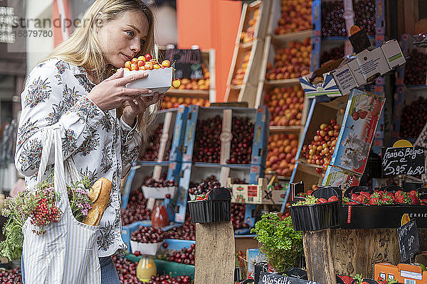 Junge Frau kauft Früchte an einem Marktstand