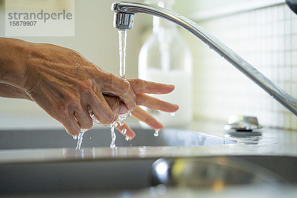Mann wäscht Hände mit Wasser im Waschbecken im Badezimmer