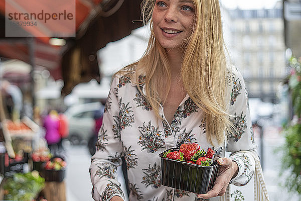 Junge Frau kauft Früchte an einem Marktstand