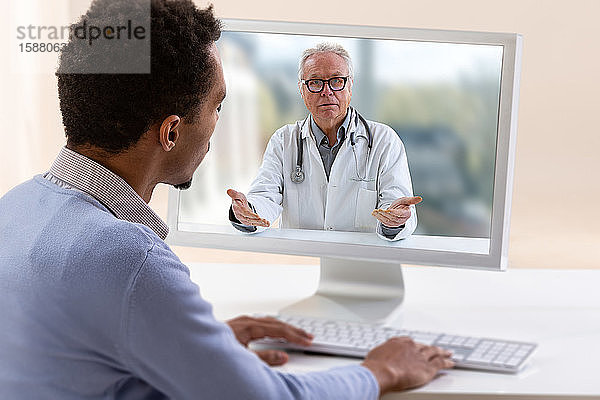 Telemedizin und Gesundheitskonzept mit einem jungen Mann und einem Arzt auf einem Computerbildschirm