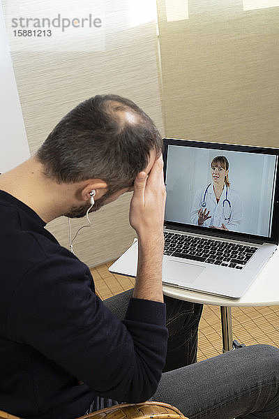 Ein Mann konsultiert seinen Arzt per Videokonferenz.