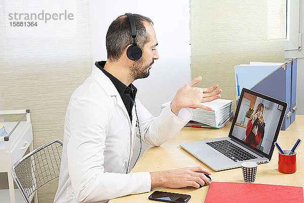 Krankenhausarzt während einer Videosprechstunde in seinem weißen Kittel.