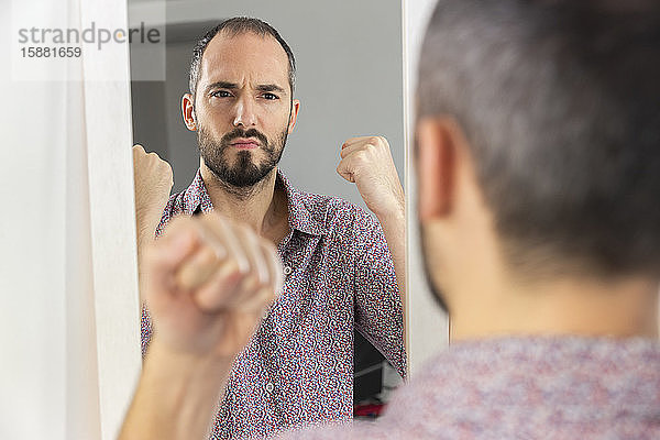 Ein Mann  der in einen Spiegel schaut  um sein Selbstvertrauen zu stärken.