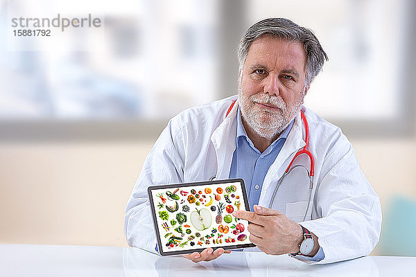 Arzt Ernährungsberater hält digitales Tablet mit Gemüse und Obst auf dem Bildschirm.