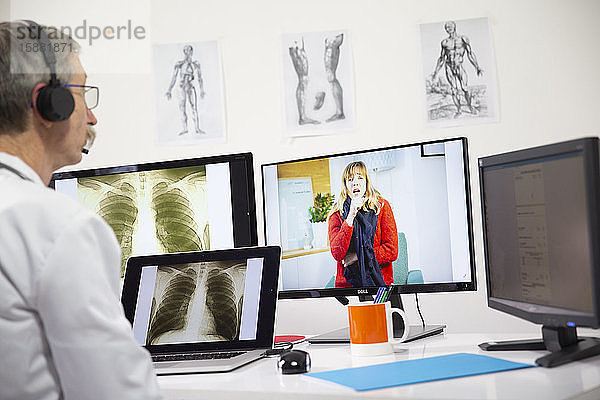 Ein Allgemeinmediziner betrachtet wÃ?hrend einer Videosprechstunde das RÃ¶ntgenbild einer Frau  die eine Lungeninfektion hat.