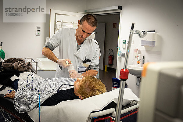 Eine Frau mit einer Fraktur des Armes. Le médecin réduit la fracture pendant que l'infirmier pose le platre.