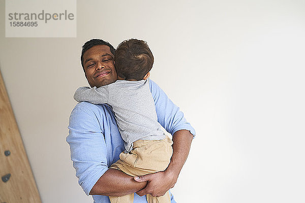 Ein Mann lächelt  hält und umarmt seinen Sohn.