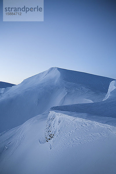 Blick auf einen schneebedeckten Berg in der Dämmerung  glatte Schneefelder ohne Spuren.