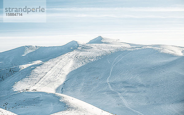 Blick auf menschenleere Skipisten in den Bergen  leere Pisten mit Schneespuren.