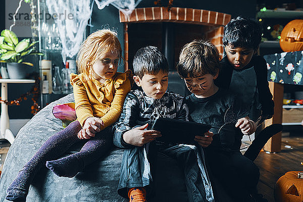 Vier Kinder sitzen auf einem Sitzsack und schauen auf ein Computertablett.
