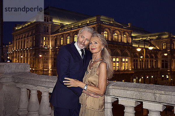 Ein älteres Ehepaar Arm in Arm an einer Balustrade während eines Abends in Wien.
