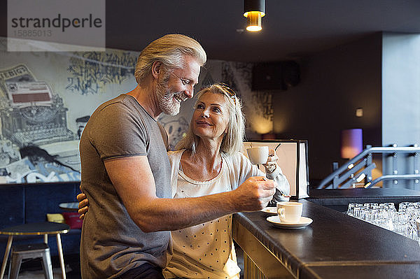 Ein Paar steht zusammen an einer Bar mit Tassen Kaffee.