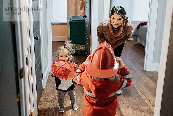 Eine Mutter lächelt ihr Kind an  das als Feuerwehrmann verkleidet ist.