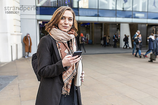 Porträt einer Frau mit Mobiltelefon vor dem Bahnhof  London  UK