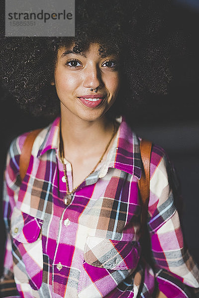 Porträt einer lächelnden jungen Frau mit Afro-Frisur