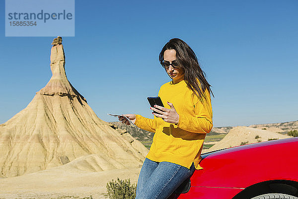 Frau betrachtet Handy in der Wüstenlandschaft von Bardenas Reales  Arguedas  Navarra  Spanien