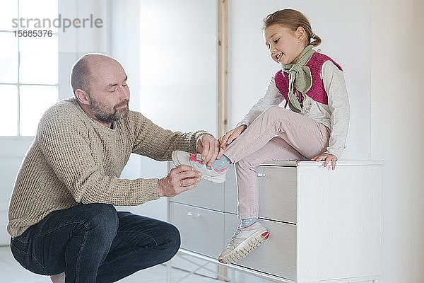 Vater hilft Tochter beim Schuhanziehen zu Hause
