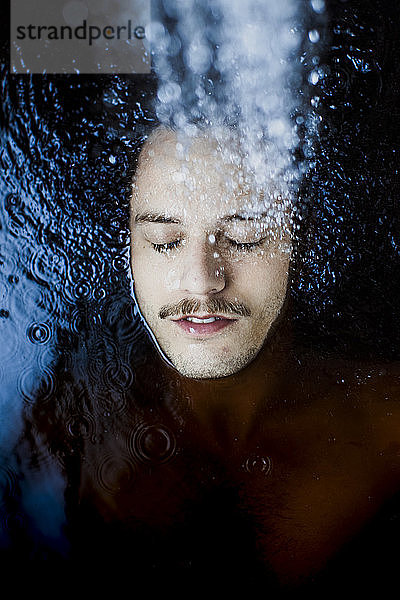 Porträt eines jungen Mannes mit geschlossenen Augen im Wasser