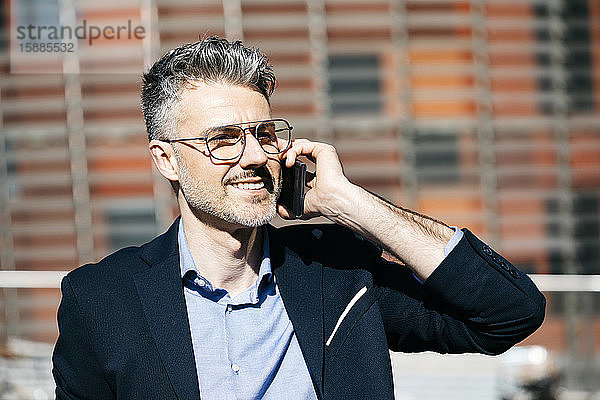 Porträt eines lächelnden grauhaarigen Geschäftsmannes am Telefon in der Stadt